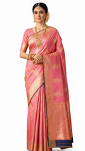 Woman wearing a pink saree with gold patterns on a white background