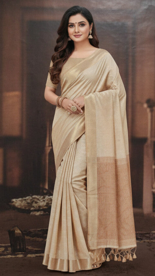 Woman wearing a beige saree with a brown border in an indoor setting