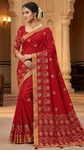 Woman wearing a red saree with gold patterns in an indoor setting